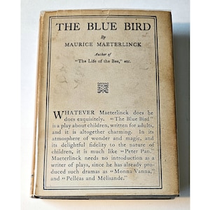 May include: A vintage book cover with the title "THE BLUE BIRD" by Maurice Maeterlinck. The cover is cream-coloured with black text and a decorative border.