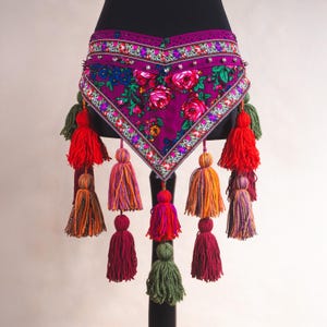 May include: A decorative belt with a heart-shaped design, featuring a vibrant floral pattern in shades of pink, red, and blue. The belt is adorned with colorful tassels in various hues, including red, orange, and green, and embellished with rhinestones.