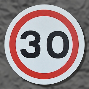 May include: A circular road sign featuring a white background, a red border, and the number 30 in black. This sign indicates a speed limit of 30 miles per hour, equivalent to approximately 48 kilometers per hour.