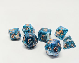 May include: A set of seven blue and white dice with copper-colored numbers. The dice are made of resin and have a glittery finish.