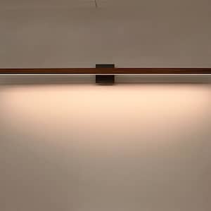 May include: A modern wall-mounted light fixture with a wooden frame and a black metal base. The light is turned on and emits a warm white glow.