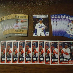 May include: A collection of baseball trading cards featuring Mookie Betts. The cards are from different years and include a high school rookie card, a Los Angeles Dodgers card, and a Boston Red Sox card. The cards are all in good condition and would be a great addition to any baseball card collection.