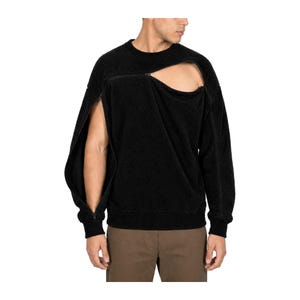 May include: A black long-sleeve sweatshirt with a textured fleece-like finish. The garment features a prominent diagonal zipper detail extending from the neckline across the chest and down the right sleeve, creating an open cutout effect.