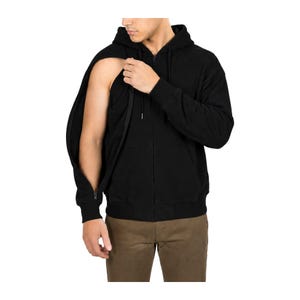 May include: A black zip-up hoodie featuring a full-length zipper along the right sleeve, allowing the arm to be exposed. The garment includes a hood with drawstrings, ribbed cuffs, and a front zipper closure, worn over plain brown trousers.