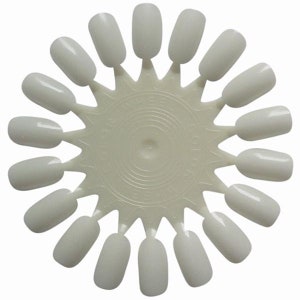 Peut inclure: Un nuancier de vernis à ongles en plastique blanc avec 18 pointes d'ongles individuelles. Chaque pointe est peinte avec une nuance de blanc différente.