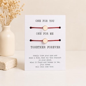 May include: Two red string bracelets with small gold-toned circular charms attached to a white card. The card features the text ONE FOR YOU, ONE FOR ME, TOGETHER FOREVER, and instructions about making a wish when the bracelet frays and breaks.