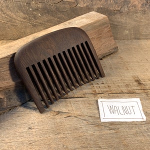 K&ouml;nnte beinhalten: Ein dunkelbrauner Holzkamm mit abgerundeter Oberseite und einem Etikett mit der Aufschrift "WALNUT".