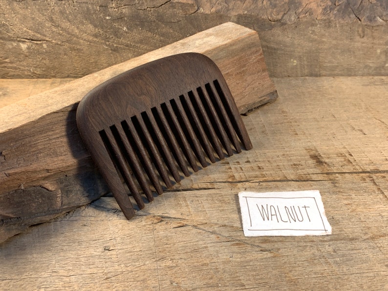 K&ouml;nnte beinhalten: Ein dunkelbrauner Holzkamm mit abgerundeter Oberseite und einem Etikett mit der Aufschrift "WALNUT".