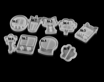 May include: A collection of nine clear silicone molds in various shapes, including a circle, a rectangle, a cat, a flower, a house, a key, a video game controller, a snow globe, and a paw print. Each mold is numbered.