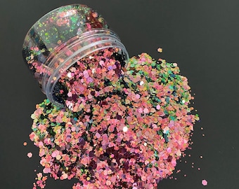 Könnte beinhalten: Ein klarer Plastikbehälter, der umgekippt ist und einen Haufen schillernder Glitzer verstreut. Der Glitzer ist eine Mischung aus rosa, grünen und lila sechseckigen Formen. Der Hintergrund ist einfarbig schwarz.