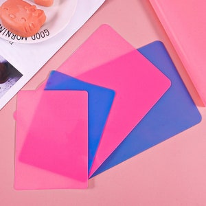 K&ouml;nnte beinhalten: Vier Silikon-Backmatten in Rosa und Blau. Die Matten sind &uuml;bereinander gelegt, wobei die rosa Matten oben und die blauen Matten unten liegen.