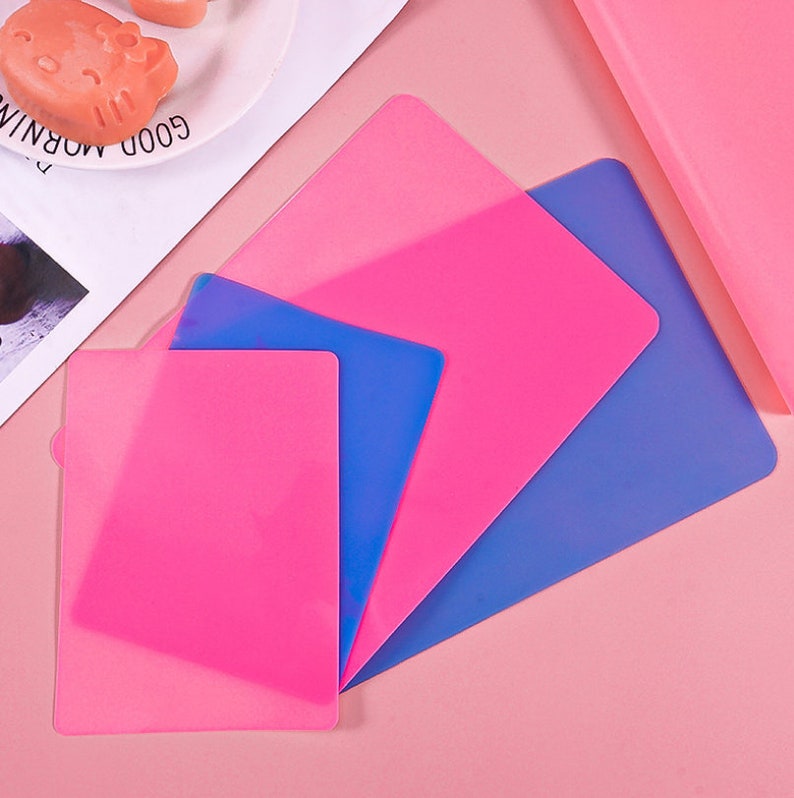 K&ouml;nnte beinhalten: Vier Silikon-Backmatten in Rosa und Blau. Die Matten sind &uuml;bereinander gelegt, wobei die rosa Matten oben und die blauen Matten unten liegen.