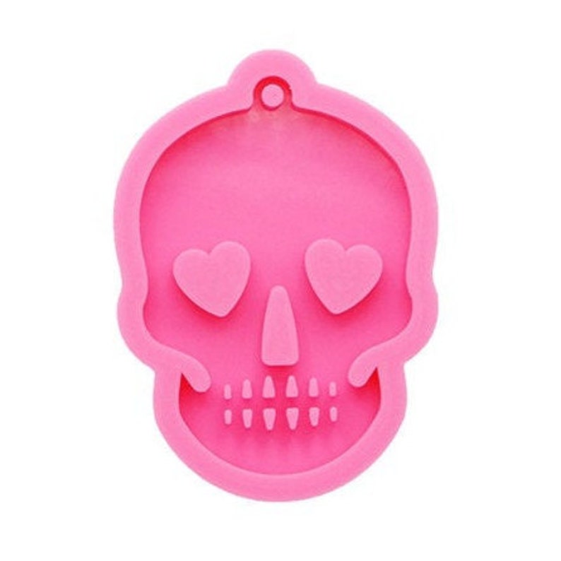 May include: Pink silicone mold shaped like a skull with heart-shaped eyes. The mold is designed for making resin crafts.