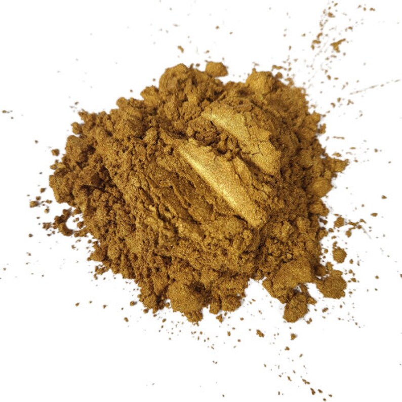 May include: A pile of loose gold mica powder. The powder is a fine, shimmery gold color and is used for adding sparkle to crafts and projects.