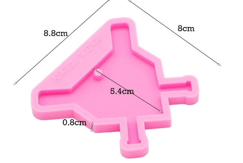 May include: Pink silicone mold shaped like a house with a pointed roof and a chimney. The mold is 8 cm tall, 8.8 cm wide, and 5.4 cm deep. The mold has the text "ANGEL WINGS" on the side.