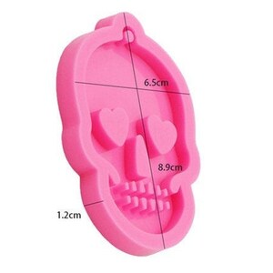 May include: Pink silicone mold shaped like a skull with heart-shaped eyes. The mold measures 6.5 cm wide, 8.9 cm tall, and 1.2 cm thick.