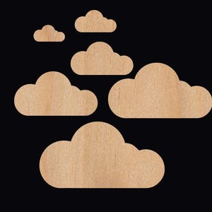 May include: A set of six wooden cloud shapes in various sizes. The clouds are cut from a light brown wood and have a natural wood grain finish.