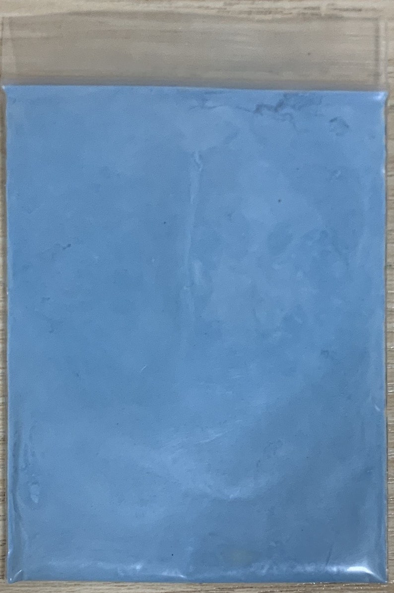 May include: A bag of light blue powder. The powder is smooth and uniform in texture.