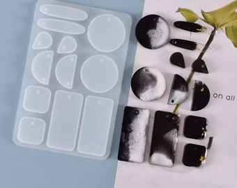 May include: A clear silicone mold with 15 different shapes for making resin earrings. The mold includes circles, ovals, rectangles, and half-circles. There are also several finished resin earrings in black and white with gold flakes.