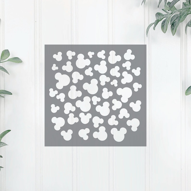 K&ouml;nnte beinhalten: Ein grauer Hintergrund mit einem wei&szlig;en, sich wiederholenden Muster aus Mickey-Maus-K&ouml;pfen in verschiedenen Gr&ouml;&szlig;en.