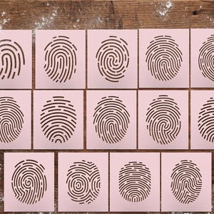 May include: A collection of pink square stencils featuring various fingerprint patterns. The stencils are arranged on a wooden surface, with a scattering of white powder in the background. The fingerprints vary in design, showcasing different ridge patterns.