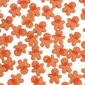 Op de afbeelding: Een verzameling kleine, bruine gingerbread man-versieringen met rode strikjes en lachende gezichten. Deze decoratieve stukken zijn verspreid over een witte achtergrond.