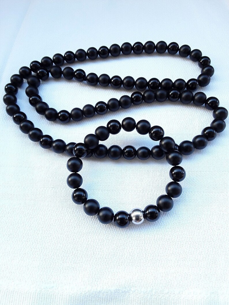 May include: A black onyx beaded necklace and bracelet set. The necklace is longer and the bracelet has a silver bead accent.