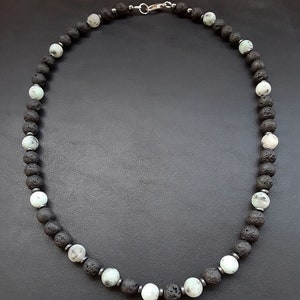May include: A black and white beaded necklace with a silver clasp. The necklace is made of lava rock and white agate beads.