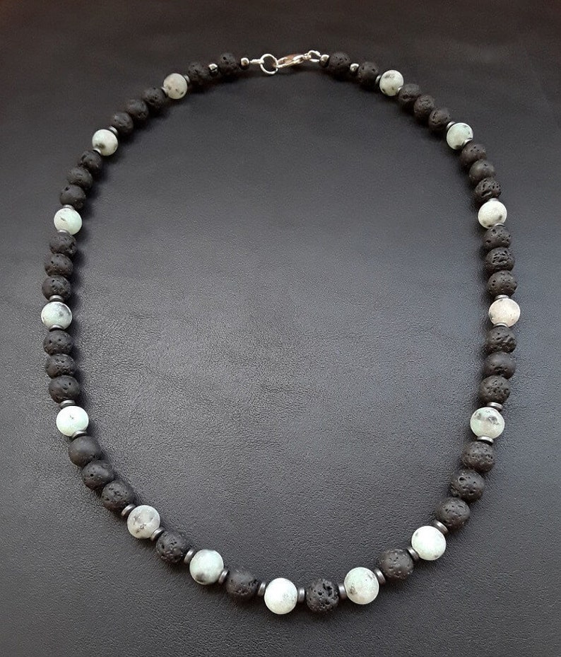 May include: A black and white beaded necklace with a silver clasp. The necklace is made of lava rock and white agate beads.