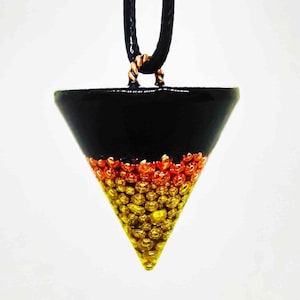 May include: A black, gold, and orange triangular pendant with a black cord. The pendant is filled with small gold and orange beads.