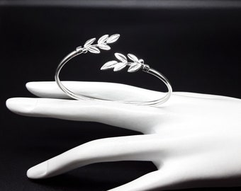 May include: Silver ring with a leaf design. The ring is open and adjustable.