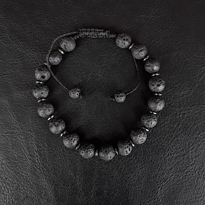 以下が含まれることがあります： 黒いビーズと黒い紐、銀色のアクセントが付いたブレスレット。ビーズは溶岩で作られています。