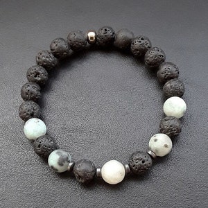 May include: A black lava rock and white gemstone beaded bracelet with a silver accent.