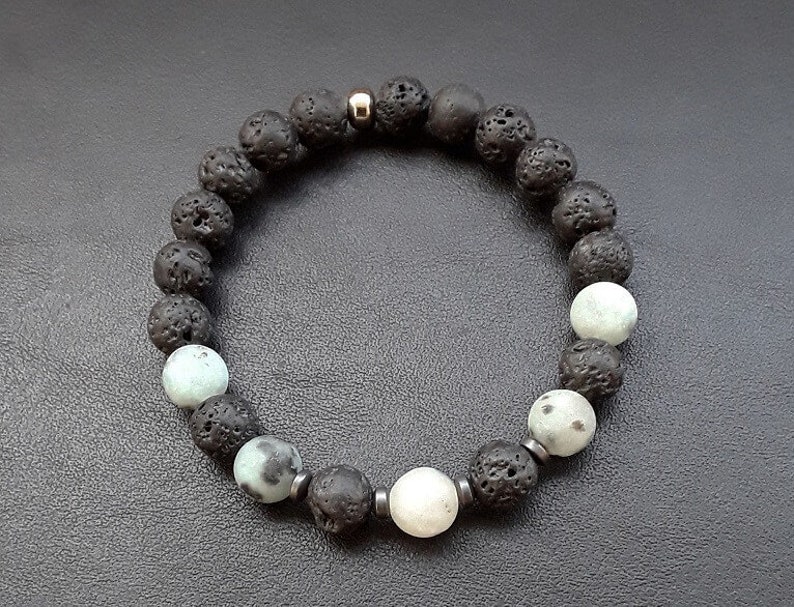 May include: A black lava rock and white gemstone beaded bracelet with a silver accent.