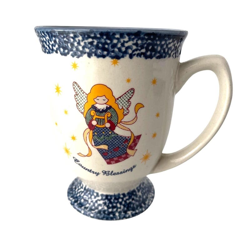 Pu&ograve; includere: Tazza in ceramica bianca con bordo e base maculati blu. La tazza presenta un angelo dei cartoni animati che suona l'arpa, con stelle gialle sparse. Le parole "Country Blessings" sono stampate sulla tazza.