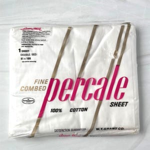 May include: A white double bed sheet packaged in clear plastic. The label reads Fine Combed Percale Sheet, 100% Cotton, 81 x 108 inches, and W.T. Grant Co. The packaging features bold pink text and gold diagonal lines across the front surface.