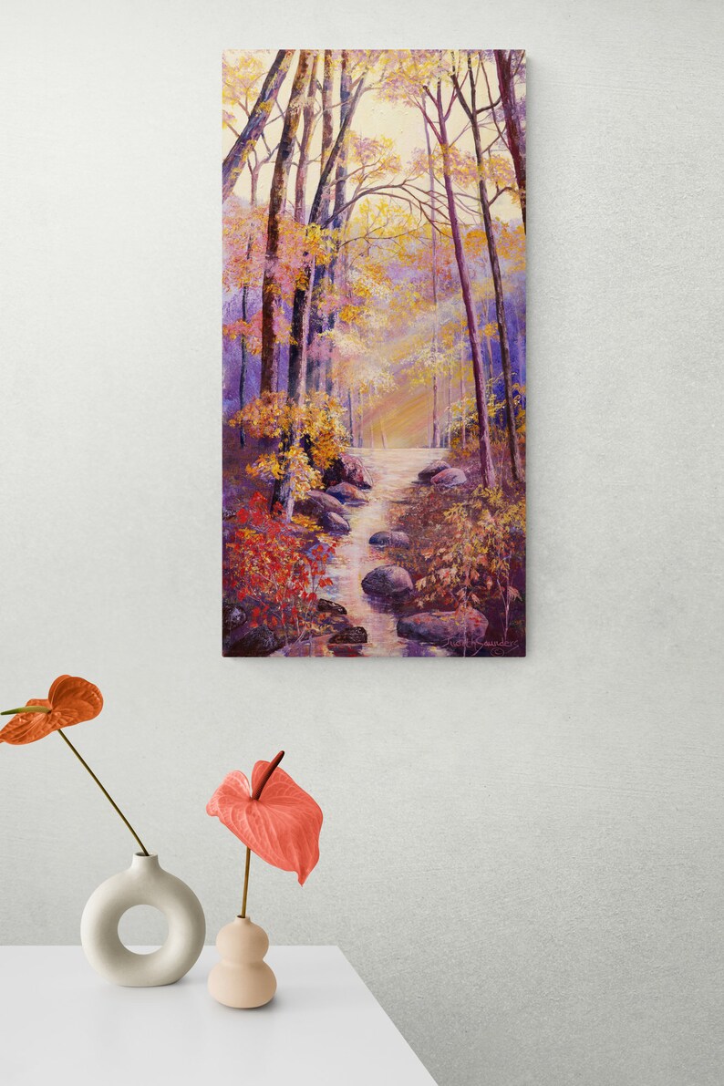 May include: A painting of a forest path with a stream running through it. The trees are mostly bare, but some have leaves in shades of yellow, orange, and red. The stream is clear and flowing over rocks. The sun is shining through the trees, creating a warm glow.