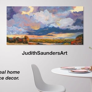May include: A painting of a landscape with a cloudy sky in shades of purple, blue, and yellow. The landscape features a river, trees, and a field. The text "JudithSaundersArt" is below the painting. The text "The ideal home or office decor." is below the text.