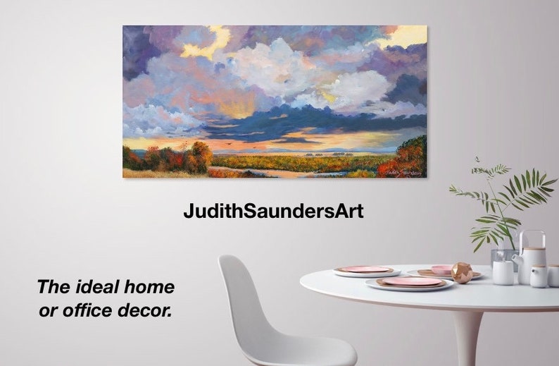 May include: A painting of a landscape with a cloudy sky in shades of purple, blue, and yellow. The landscape features a river, trees, and a field. The text "JudithSaundersArt" is below the painting. The text "The ideal home or office decor." is below the text.