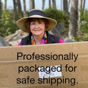 May include: A woman holds a cardboard box with the text "Professionally packaged for safe shipping" printed on it.