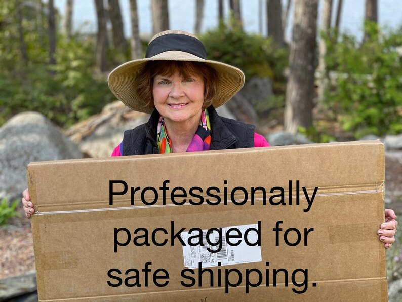 May include: A woman holds a cardboard box with the text "Professionally packaged for safe shipping" printed on it.