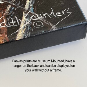May include: Close-up of the edge of a canvas print with a black frame. The print has a white signature that reads "Judith Saunders". The text below the signature reads "Canvas prints are Museum Mounted, have a hanger on the back and can be displayed on your wall without a frame."