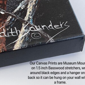 May include: Close-up of a black canvas print with a white signature that reads "Judith Saunders". The print is mounted on 1.5 inch basswood stretchers with black edges and a hanger on the back.
