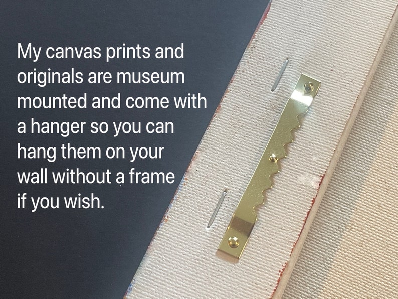 May include: Close-up of a gold-colored sawtooth hanger attached to the back of a canvas print. The hanger is designed to hang the print on a wall without a frame.