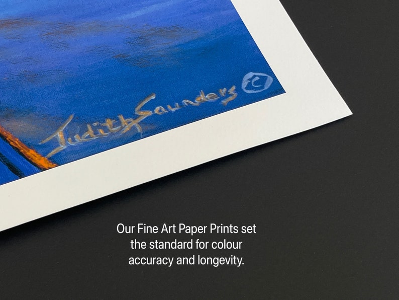 May include: A close-up of a white matted print with a blue and orange painting. The artist's signature, "Judith Saunders", is visible in the bottom right corner of the print. The text "Our Fine Art Paper Prints set the standard for color accuracy and longevity." is printed below the mat.