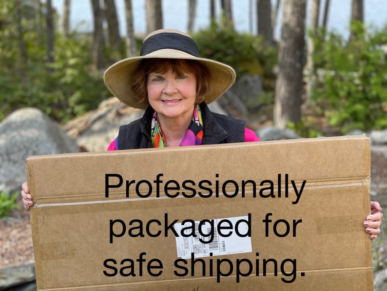 May include: A woman holds a cardboard box with the text "Professionally packaged for safe shipping" printed on it.