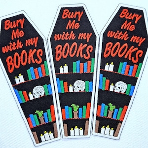 May include: Three coffin-shaped embroidered patches with black backgrounds. Each features the orange text "Bury Me with my BOOKS" above shelves containing colourful books, white skulls, green potted plants, and white candles with yellow flames.