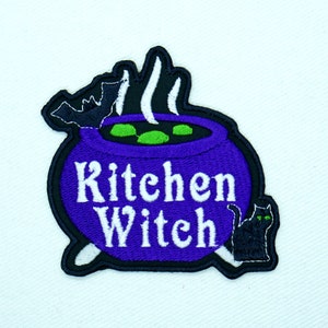 May include: Purple embroidered iron-on patch with a cauldron, steam, bats, a black cat, and the text "Kitchen Witch".