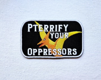 May include: Black embroidered patch with a yellow pterodactyl and the text "PTERRIFFY YOUR OPPRESSORS".