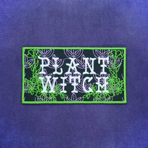 May include: A black embroidered patch with a green border. The patch features a floral design and the text "PLANT WITCH".